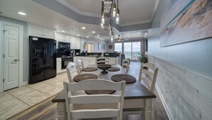 A spacious kitchen with white cabinetry, a black refrigerator, and a dining area with a wooden table and chairs.