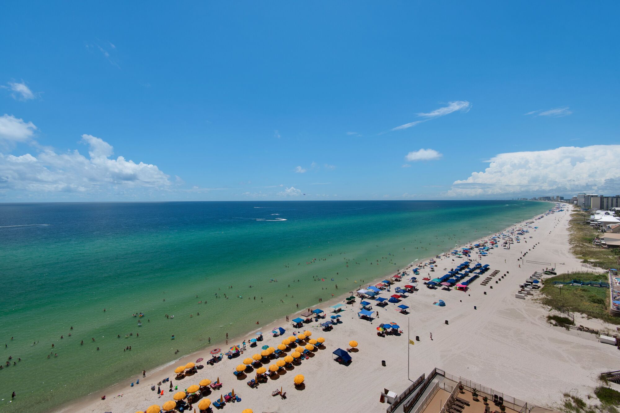 Una playa con aguas turquesas cristalinas, una orilla arenosa y numerosos sombrillas.