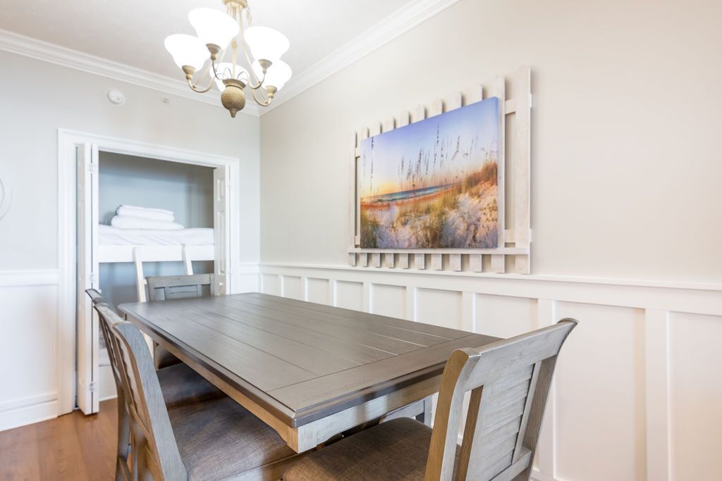 Un coin repas avec une table et des chaises en bois, un lustre et un tableau au mur.