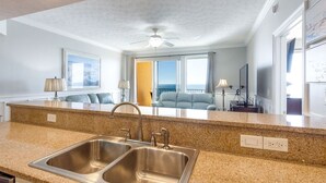 Une cuisine moderne dotée de plans de travail en granit, d’éviers en acier inoxydable et d’un ventilateur de plafond.