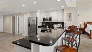 A modern kitchen with white cabinets, stainless steel appliances, and a black countertop. - Treasure Island 1208 (Panama City Beach)