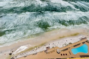Vista aérea de una playa con piscina y zona de descanso.