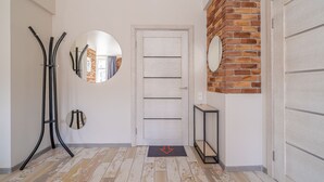 Un corridoio con una porta bianca, uno specchio, un tavolino e una parete decorata con mattoni.
