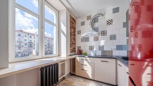 Una cucina con una finestra, termosifone e piastrelle decorate.