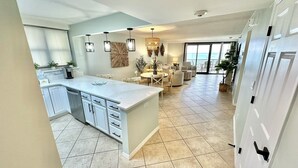 A spacious kitchen with a large island, white cabinetry, and a dining area with a round table and chairs. - Stunning Beachfront Unit Great Views Golf Cart4045 (Miramar Beach)