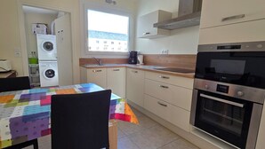 Eine kompakte Küche mit Waschmaschine, Kaffeemaschine und einem großen Backofen.