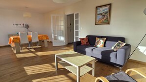 Ein Wohnzimmer mit einer Couch, einem Couchtisch und einem Esstisch mit Stühlen.