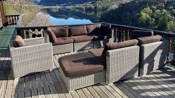 Una terraza con muebles de mimbre y vistas a un lago y montañas.