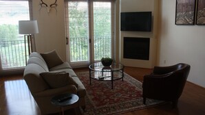 Ein Wohnzimmer mit einer Couch, einem Couchtisch, einem Sessel und einem Fernseher.
