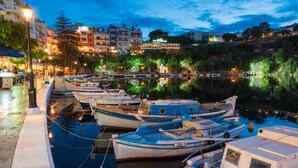 A marina with several boats docked, a waterfront promenade, and buildings in the background. - Modern hilltop villa with pool near Agios Nikolaos (Vathi)