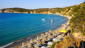 A beach with clear blue water, a sandy shore, and a wooden walkway. - Modern hilltop villa with pool near Agios Nikolaos (Vathi)