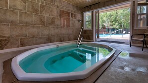 A spa area with a hot tub, stone walls, and a view of a pool and trees outside. - Quiet Keystone Studio with Mountain Views, Near Shuttle Stop & Hiking Trails! (Keystone)