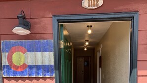 A hallway with a red exterior, a green door, and a carpeted entrance. - Lake Front Rental/Downtown Grand Lake
Apt 1 The Chickadee (Grand Lake)