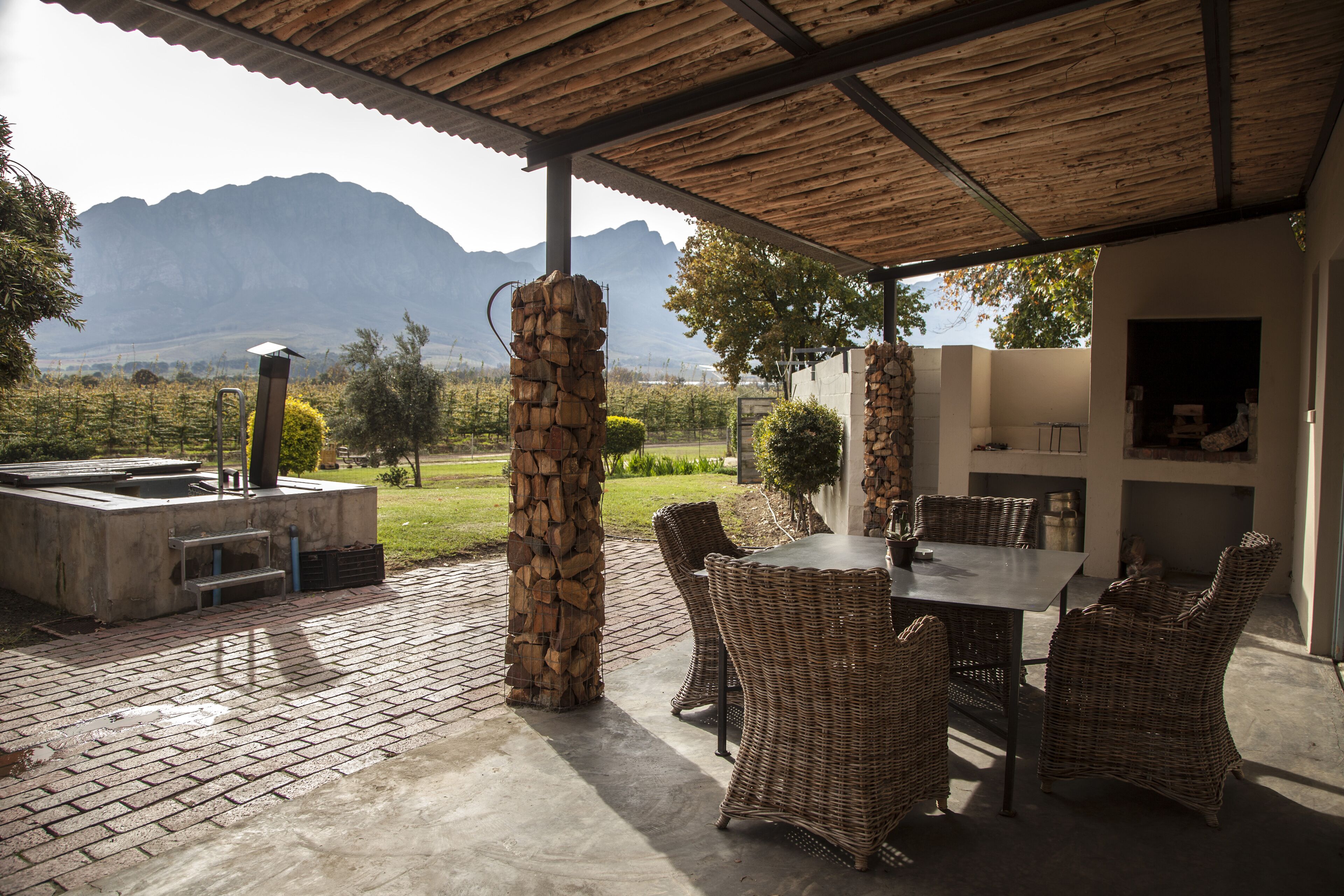 Un patio exterior con un pilar de piedra, muebles de mimbre y vistas a montañas.