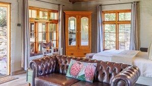 A room with a wooden cabinet, a leather sofa, and a bed. - Bergsicht Country Farm Cottages (Tulbagh)