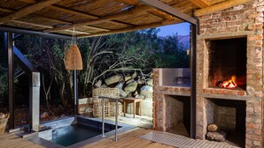 An outdoor patio with a brick fireplace, a hot tub, and a wooden deck. - Bergsicht Country Farm Cottages (Tulbagh)