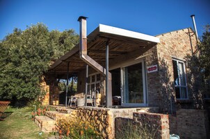 A stone building with a covered patio, a chimney, and a sign indicating a restaurant.