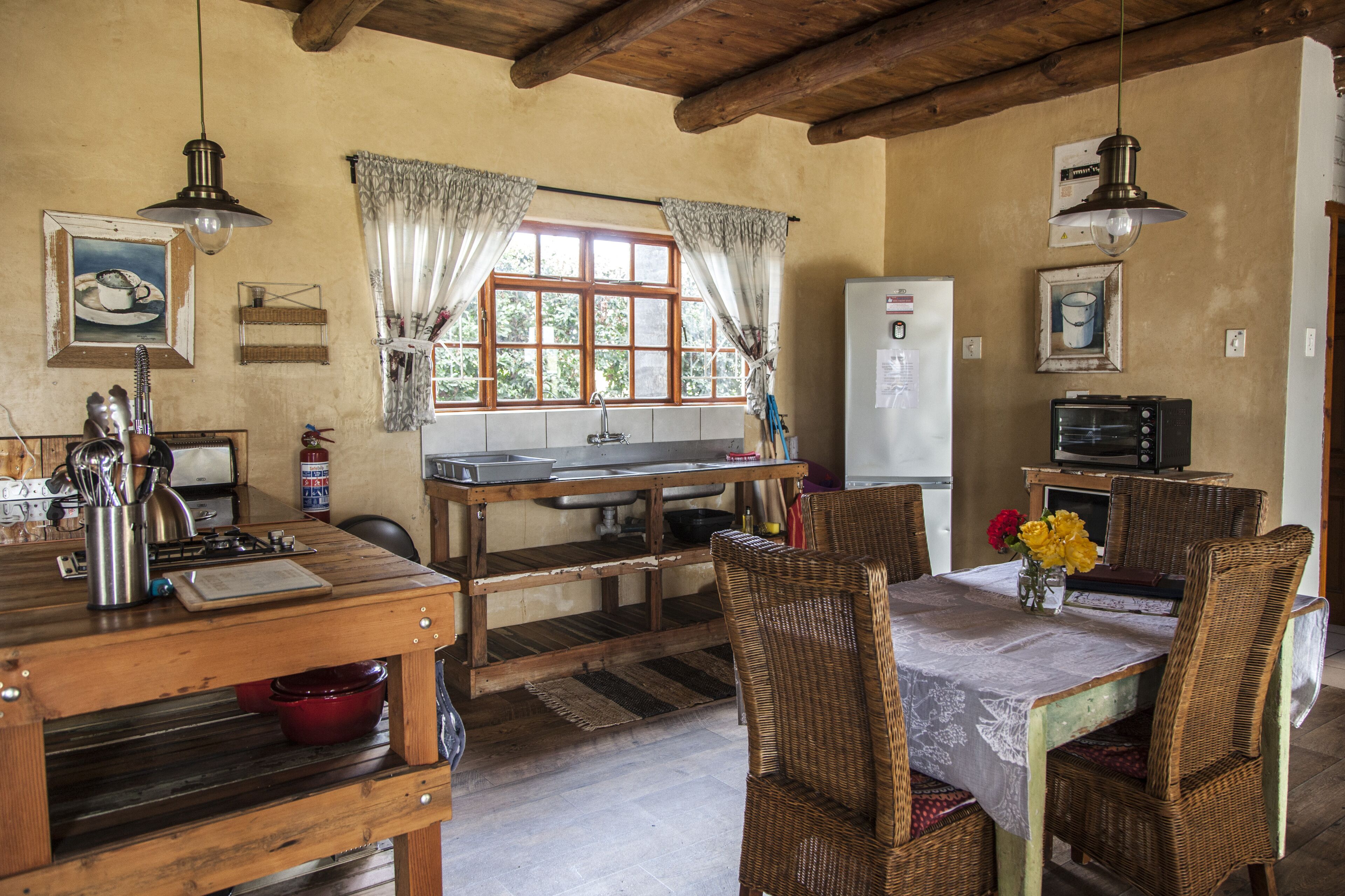 A rustic kitchen with wooden furniture, a dining table, and a refrigerator.