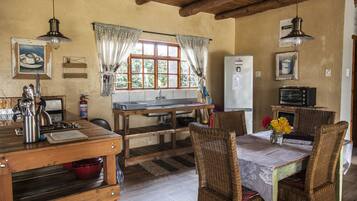 A rustic kitchen with wooden furniture, a dining table, and a refrigerator.