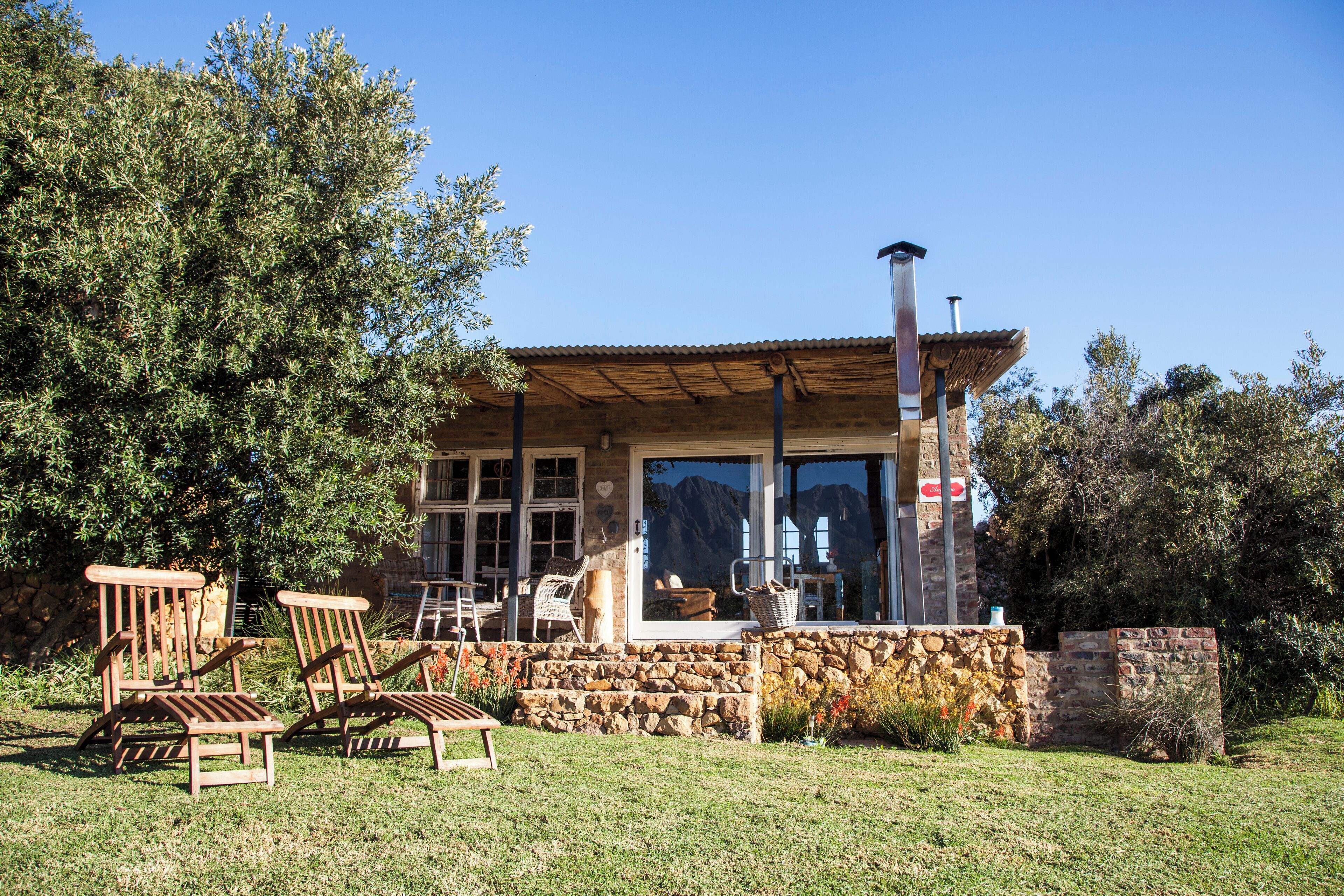 A stone building with a wooden deck, outdoor seating, and a mountain view.