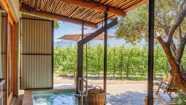 A wooden deck with a hot tub, wicker chairs, and umbrellas. - Bergsicht Country Farm Cottages (Tulbagh)