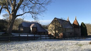 A traditional building with a sloped roof and a large tree in the foreground.