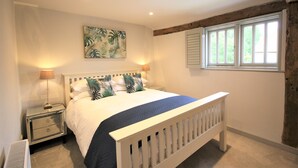 A bedroom with a bed, nightstands, a window, and a painting on the wall. - 3 Weaver's Cottage - ideal retreat for exploring (Benenden)