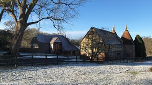 Un bâtiment traditionnel avec un toit en pente et un grand arbre au premier plan.