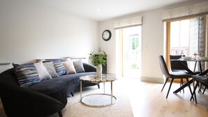 Un salon moderne avec un canapé foncé, une table basse ronde et un coin repas comprenant des chaises et une table.