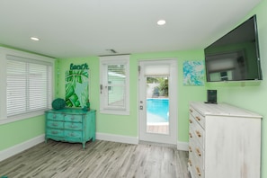 A room with a pool, a teal dresser, a white cabinet, and a TV on the wall. - Beach Breeze (Anna Maria)