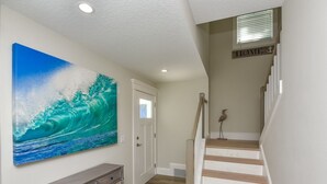 A staircase with wooden steps and a white handrail, leading to a landing with a door and a wall-mounted sign reading "HOME". - Ocean Breeze (Bradenton Beach)