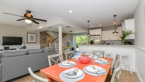 Une cuisine moderne avec des meubles blancs, une table à manger dressée et un ventilateur de plafond.
