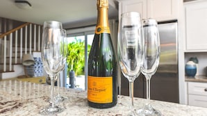 Une bouteille de champagne brut Veuve Clicquot sur un plan de travail de cuisine, avec trois verres à vin vides.