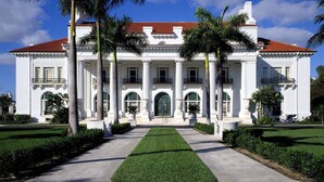 A large white building with a red-tiled roof, surrounded by palm trees and a well-maintained lawn. - You will Love this Charming Townhouse in West Palm Beach, West Palm Beach Villa 1862 (West Palm Beach)
