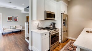 A modern kitchen with white cabinetry, stainless steel appliances, and a patterned rug. - You will Love this Charming Townhouse in West Palm Beach, West Palm Beach Villa 1862 (West Palm Beach)