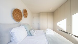 Un dormitorio moderno con una cama grande, dos adornos redondos de madera en la pared, un armario y una ventana que deja entrar luz natural.