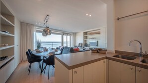 Una cocina moderna con una isla central, comedor y vistas al mar.