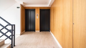 A hallway with two black doors, a wooden wall, and a staircase with black railings. - Savory Beige Apartment, AC, Wifi !New! (Lisboa)