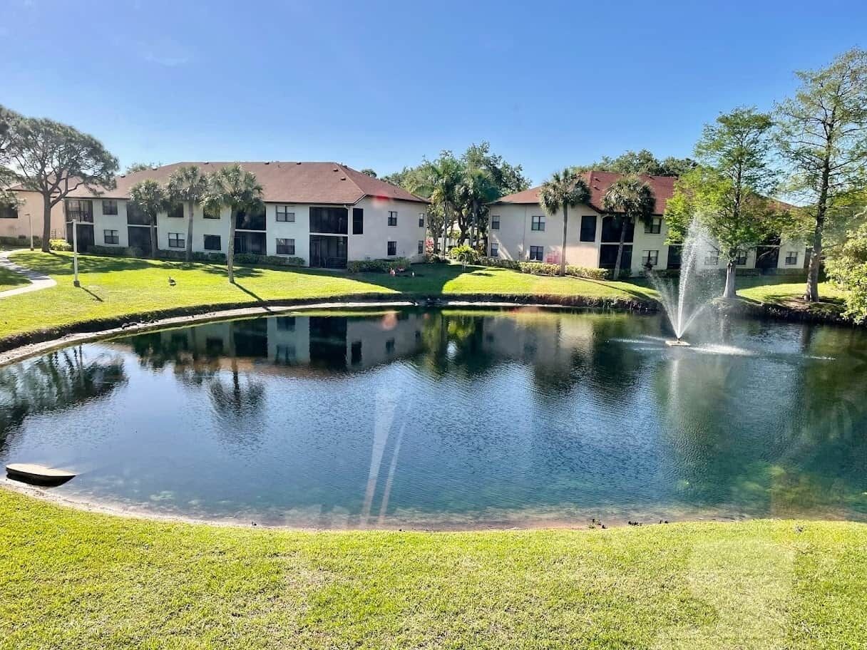 A courtyard with a fountain, a pond, and apartment buildings in the background.