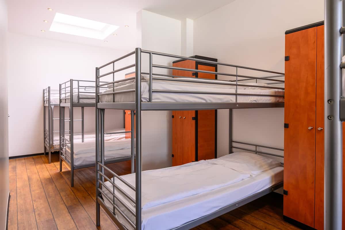 Une chambre de dortoir avec des lits superposés, un plancher en bois et une armoire.