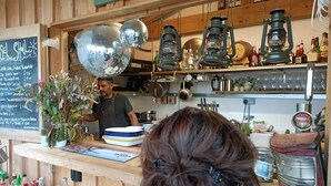 Un café à l’ambiance rustique, avec un décor intérieur en bois, un menu écrit à la craie, des boules à facettes et des lanternes d’époque.