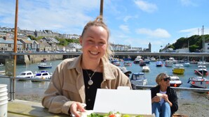 Une personne est assise à une table, devant laquelle s’étend un port rempli de bateaux.
