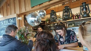 Un espace bar avec des murs en bois, une boule à facettes et des étagères remplies de bouteilles.