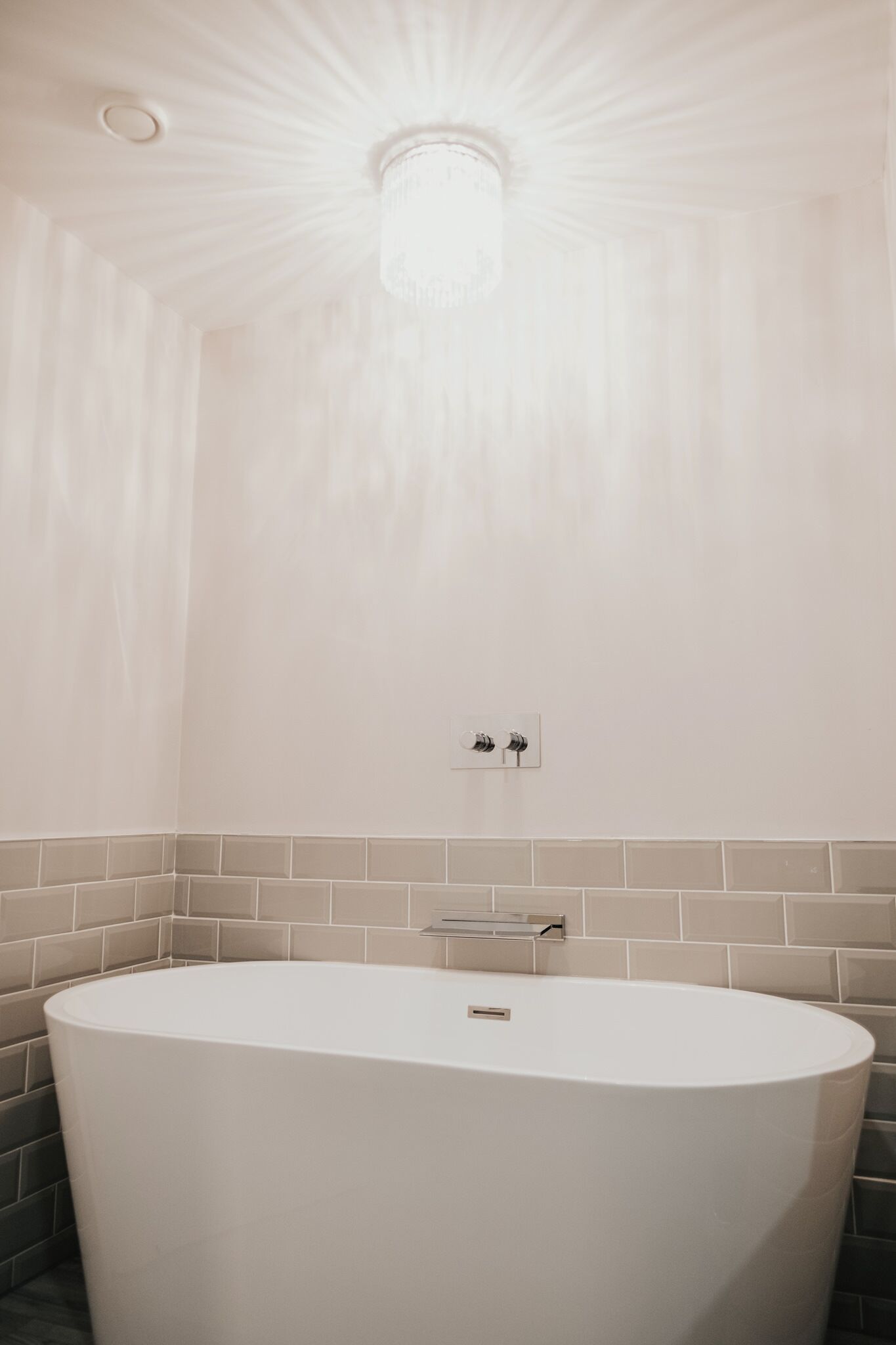 A modern bathroom with a freestanding bathtub, a ceiling light fixture, and a wall-mounted towel rack.