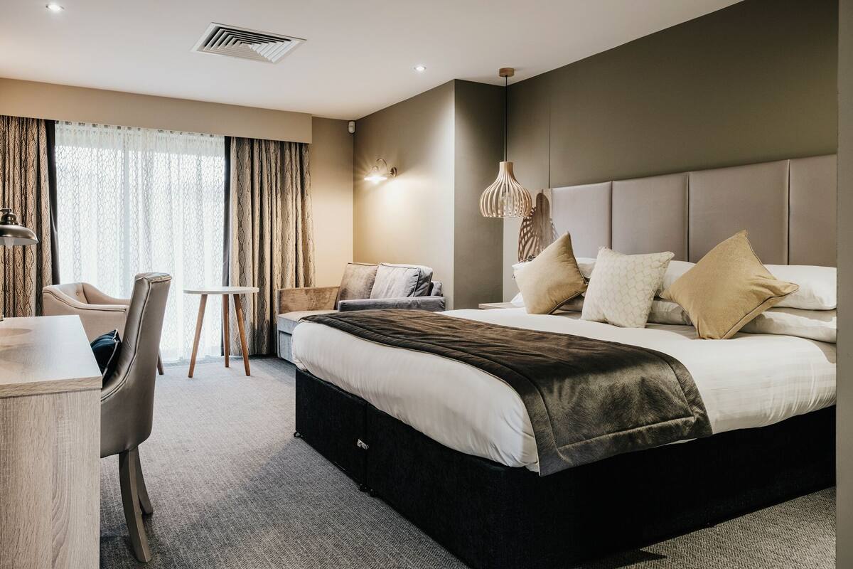 Une chambre d’hôtel moderne, dotée d’un grand lit, d’un bureau et d’une chaise.