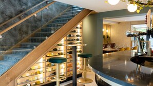 Un interior moderno con una escalera de vidrio, bodega de vinos, zona de bar y asientos.