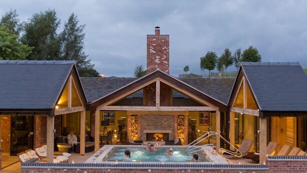 Un spa con hidromasaje, sillones de descanso y chimenea.
