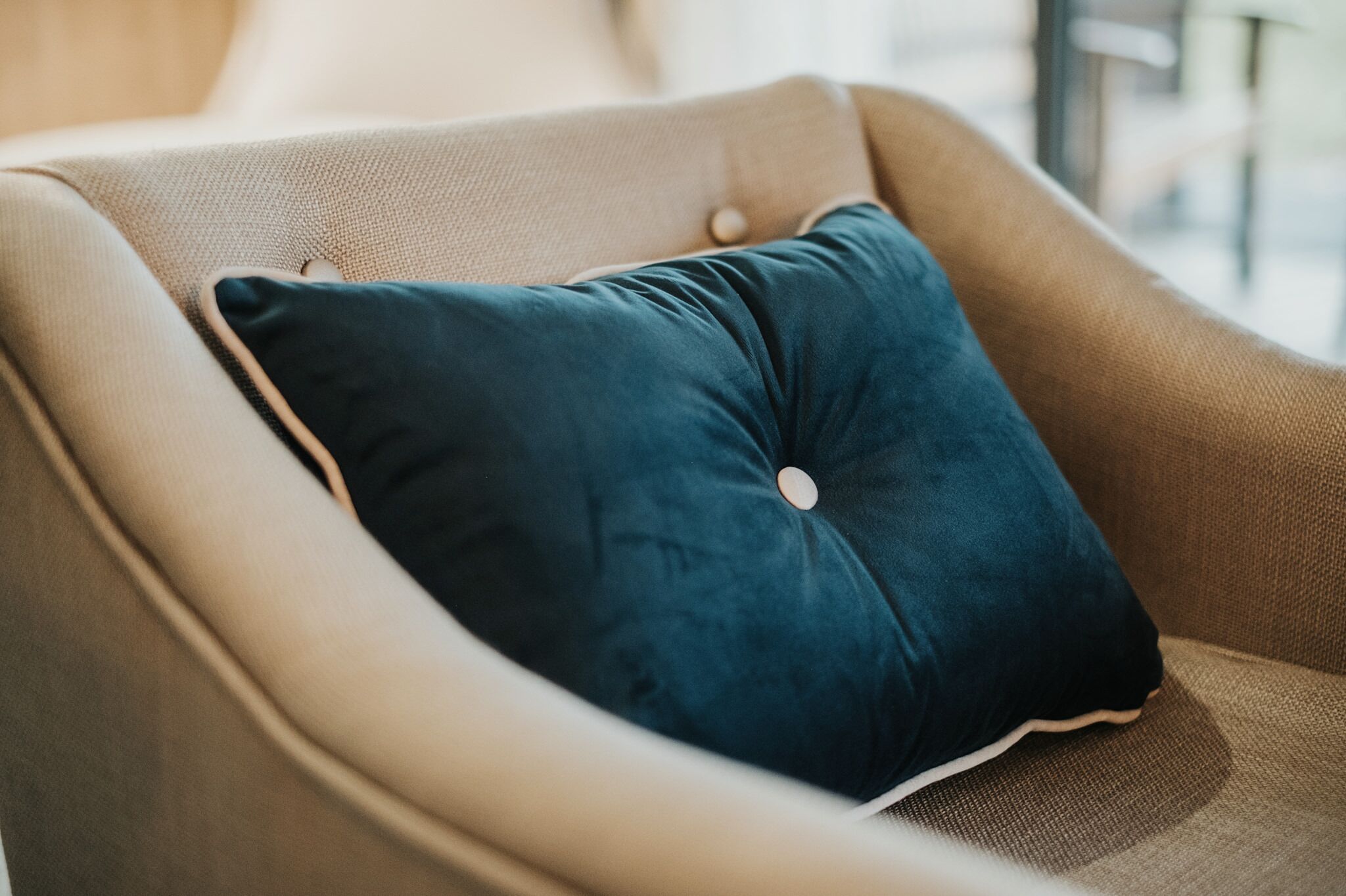 A chair with a dark blue cushion and a button detail on the armrest.