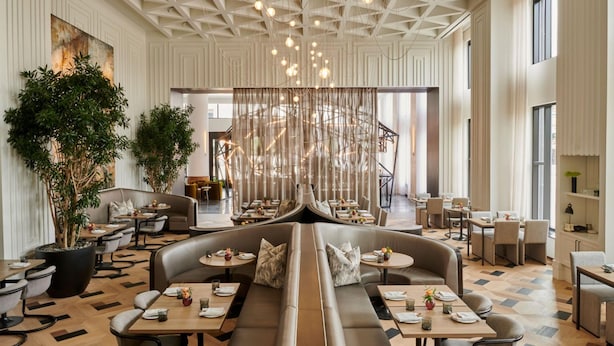 Un comedor moderno con una disposición central de asientos, techos altos con patrones geométricos e iluminación ambiental.