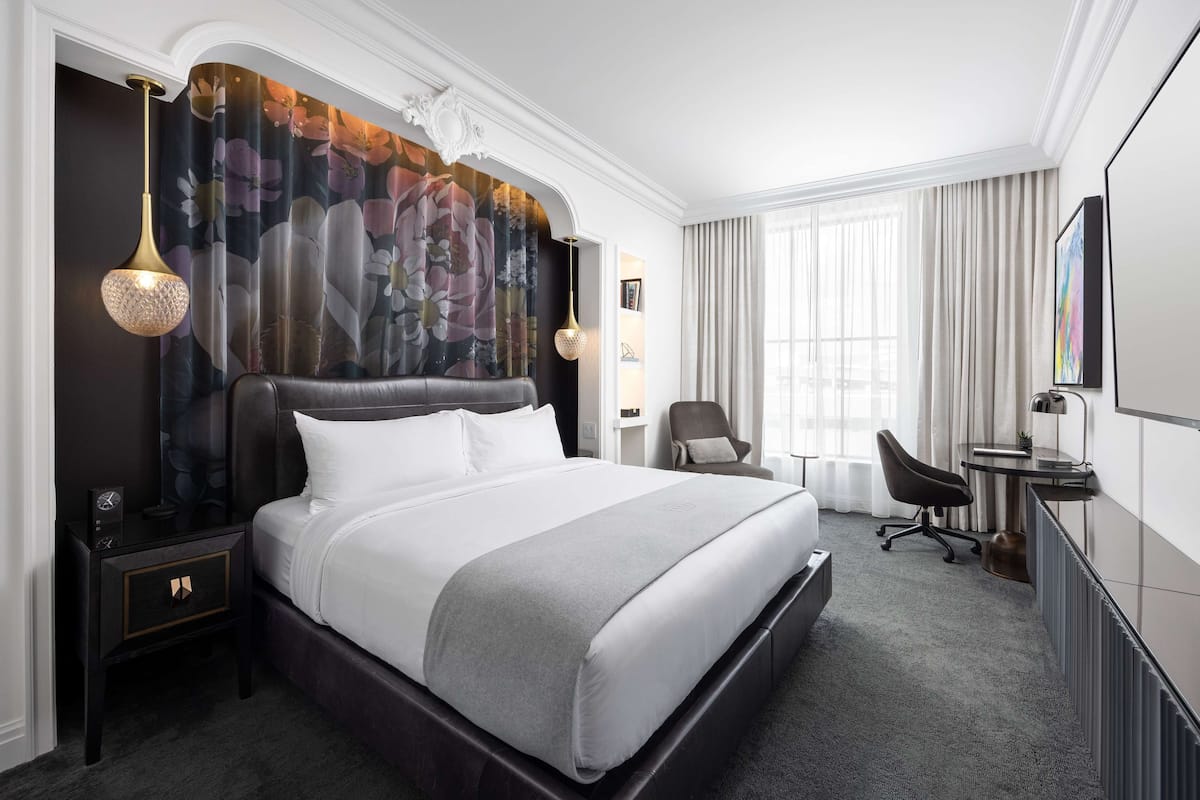 Ett modernt hotellrum med en stor säng, ett skrivbord och en stol.